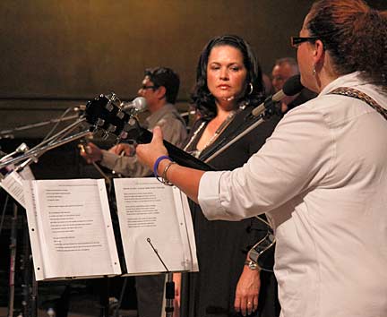 Photograph by Mark Vallen © Mayra Bermudez listens to fellow ensemble member Clara Alvear play the cuatro. Photograph by Mark Vallen ©.