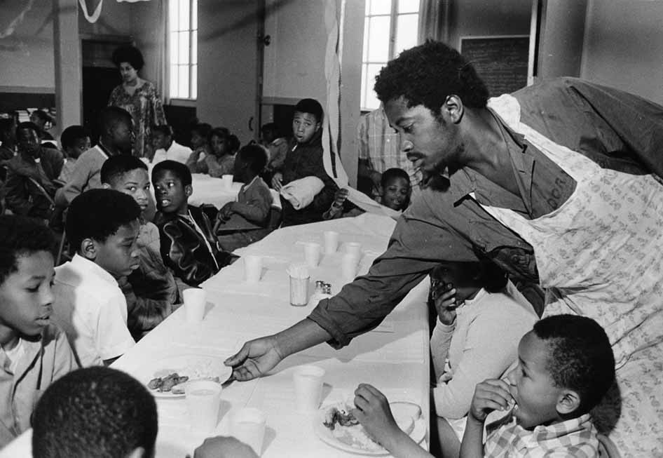 Black Panther Party member Charles Bursey serves food to children at the party's "Free Breakfast for Children" program in Oakland, California. Photo by Pirkle Jones © 1969. Courtesy of the Pirkle Jones Foundation - www.pirklejones.com