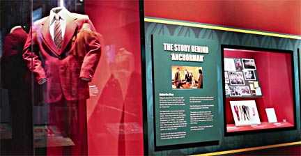 A fictitious burgundy suit belonging to a fictitious newsman, who recited fictitious news, man, all displayed at a fictitious museum back by a fictitious movie studio. Photo courtesy of a fictitious photographer.