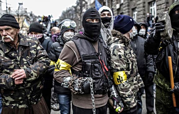 Members of the fascist "Patriots of Ukraine" organization gather for battle on the streets of Kiev, 2014. The yellow armbands display the group's symbol, a repurposed Nazi rune known as the "Wolfsangel." Photographer unknown. 