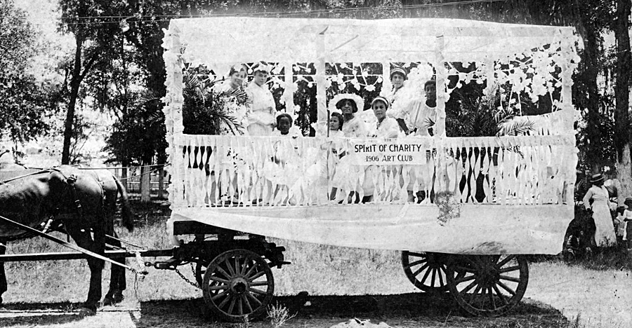 Juneteenth float decorated with white ribbons and flowers. Fixed to the float is a sign reading, “The Spirit of Charity Art Club.” 1906. Prominent families, organizations, and institutions would decorate buggies and wagons to parade them in the community before gathering in Emancipation Park for a celebration. Source: Houston Public Library.
