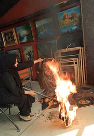 An unidentified artist in Kabul burns her paintings before the Taliban discovers her studio. Photo: Omaid Sharifi 2021